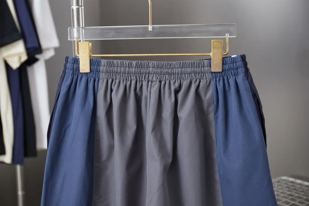 Balenciaga 𝘽𝘼𝙇𝙀𝙉𝘾𝙄𝘼𝙂𝘼 BLCG 25SS double-split waterproof sports pants. Light luxury. A must-have item for daily commuting for men and women. Correct version. Welcome to compare. Detailed features · Customized matt Taslan jacket fabric · The entire fabric is pre-treated with a waterproof coating · The interior is made of three-level polyester bird's eye mesh · OS ultra-loose silhouette design · Side pockets · Elastic waistband design · Contrast color Black webbing splicing · Front and rear contrast color splicing and cutting design · Imported Tajima machine embroidery ring logo · Original main mark washed tag brand packaging Color: White/Royal Blue Size: 46/48/50/52